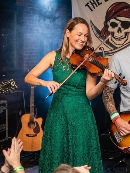 Shannon, fiddler, mid-performance in a green dress